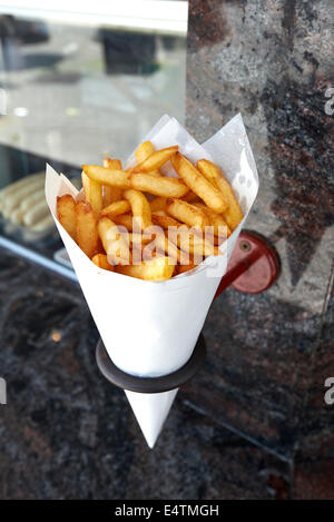 Kartoffeln Pommes frites in einer kleinen weißen Papiertüte hängen an der Wand von einem belgischen friterie Stockfoto