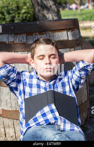 Kleiner Junge liest ein Buch im Wald mit geringer Tiefe Feld und Kopie Stockfoto