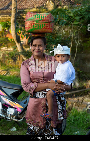 Bali, Indonesien.  Balinesische Hindu-Mutter und Sohn auf dem Weg zum Tempel.  Pura Dalem Tempel, Dlod Blungbang Dorf. Stockfoto