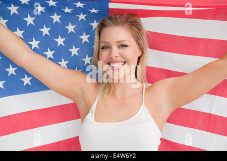 Lächelnde Frau, die die amerikanische Flagge hissen Stockfoto