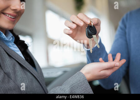 Lächelnde Frau empfangende Schlüssel aus einer hand Stockfoto