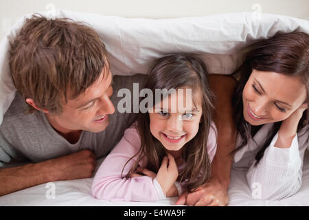 Fröhliche Familie unter einer Bettdecke liegen Stockfoto