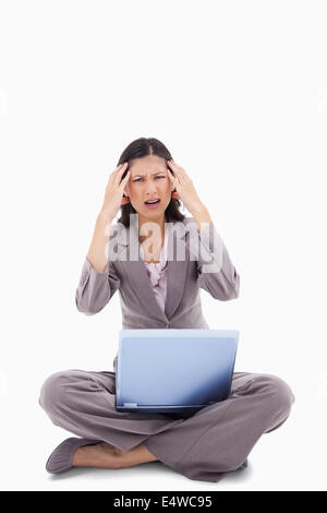 Laptop bereitet sitzende Frau Kopfschmerzen Stockfoto