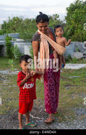 Bali, Indonesien.  Balinesischen Mutter und Kinder, tragen die jüngste in einem Schulter-Riemen. Stockfoto