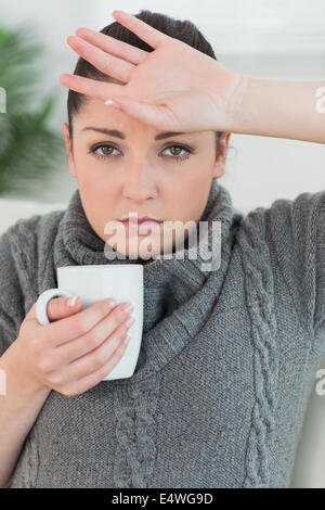 Frau auf der Couch sitzen und krank fühlen Stockfoto