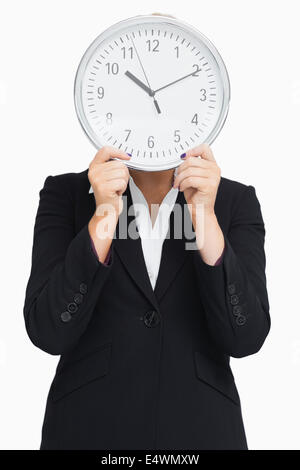 Geschäftsfrau im Anzug hält eine Uhr Stockfoto