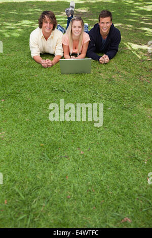 Drei lachende Schüler liegend in einem park Stockfoto