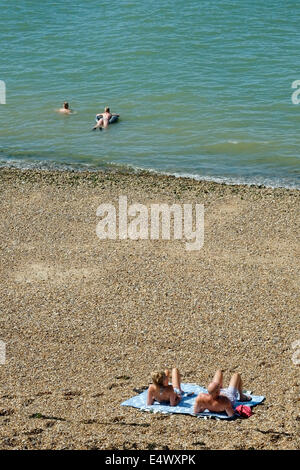 Sonnenanbeter und Schwimmer an einem heißen sonnigen Tag in Southsea uk Stockfoto