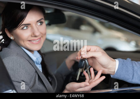 Lächelnde Frau empfangende Schlüssel von einem Mann Stockfoto