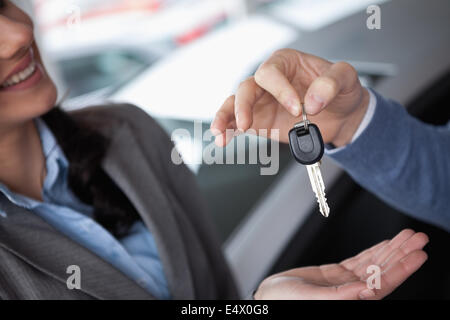 Lächelnde Frau empfangende Schlüssel von einer Person Stockfoto