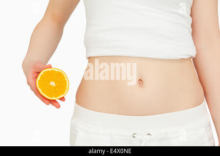 Frau eine Orange neben ihrem Bauch platzieren Stockfoto