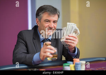 Mann mit Geld lächelnd am Roulette-Tisch Stockfoto