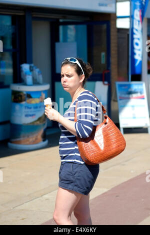 junge Frau mit einem Eis von einem Kiosk direkt am Meer an einem heißen sonnigen Tag in Southsea uk Stockfoto