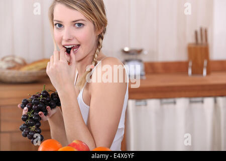 Blonde Frau essen Trauben Stockfoto