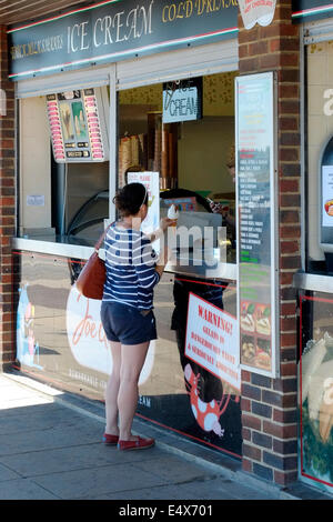 junge Frau kauft ein Eis von einem Kiosk direkt am Meer an einem heißen sonnigen Tag in Southsea uk Stockfoto