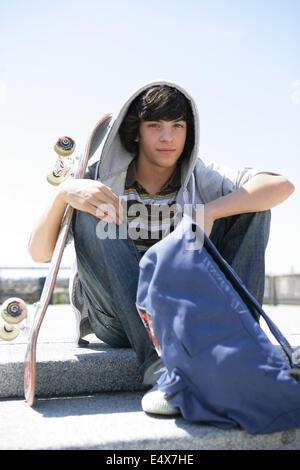 Junge sitzt auf einer Stufe mit skateboard Stockfoto