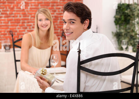 Paar im Restaurant mit Geschenk Stockfoto