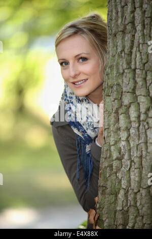 Blond, stand hinter Baum Stockfoto