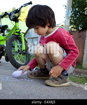 junge zeichnen mit Kreide auf asphalt Stockfoto