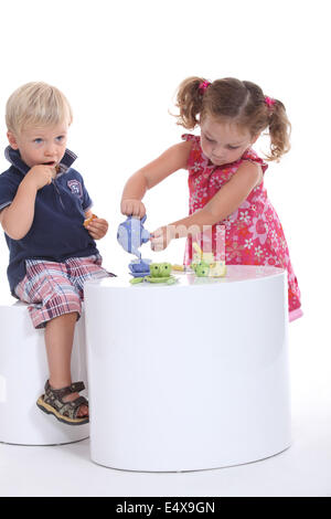 Zwei kleine Kinder, die mit einer Tee-party Stockfoto