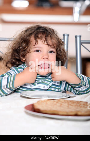 Kleinkind zieht ein Gesicht am Tisch Stockfoto