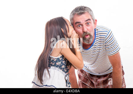 Tochter sagt Papa ein Geheimnis ins Ohr flüstern Stockfoto