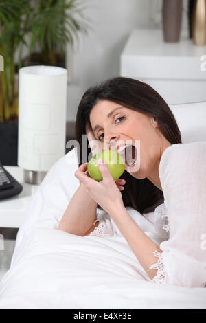 Frau Handauflegen Couch Essen Apfel Stockfoto