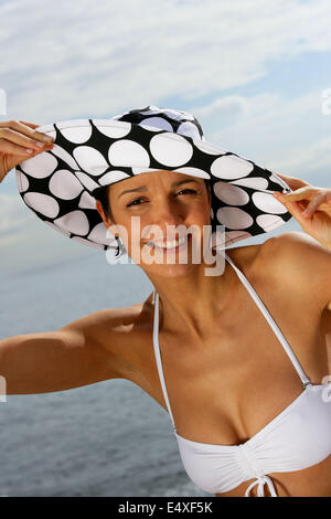 Frau mit Hut und Bikini am Strand Stockfoto