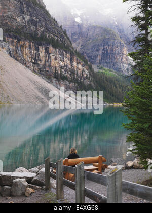 Sitzen in der Einsamkeit auf einer Parkbank am Moraine Lake im Banff National Park. Nachdenken über Leben. Stockfoto