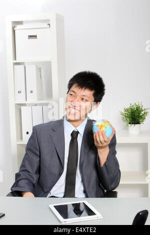 Asiatische Geschäftsmann hält kleine Weltkugel Stockfoto