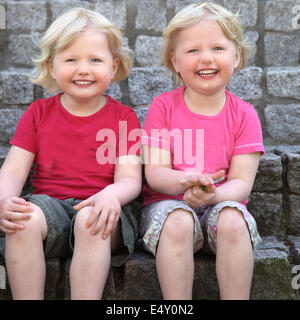 Niedliche eineiige Zwillinge lachen Stockfoto