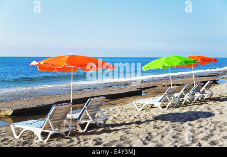 Sonnenschirmen und Liegestühlen am Sandstrand Stockfoto