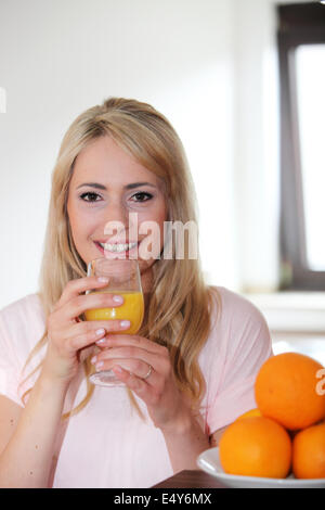 Junge Frau frischen gepressten Orangensaft trinken Stockfoto