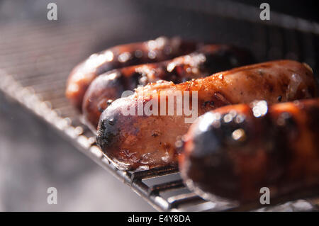 Würste Kochen auf einem Bbq grill, brutzeln und Rauchen Weg in der Sonne Stockfoto