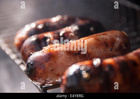 Würste Kochen auf einem Bbq grill, brutzeln und Rauchen Weg in der Sonne Stockfoto