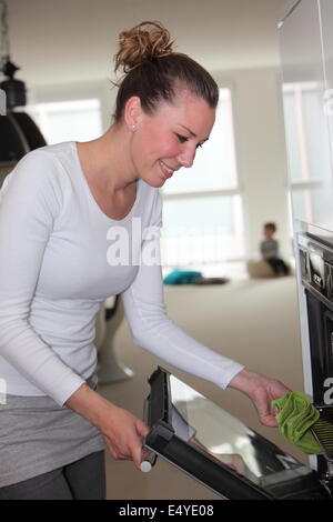 Junge Hausfrau, Essen in den Ofen setzen Stockfoto
