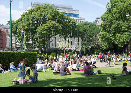 Sommertag in Victoria Embankment Gardens London britische Leute sitzen auf dem Rasen Stockfoto