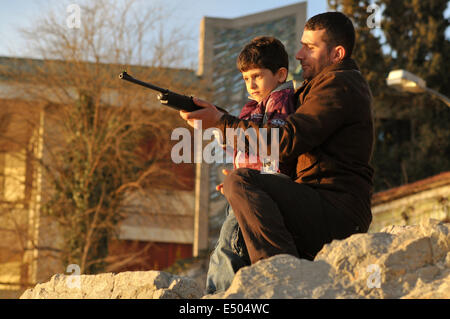 Ein türkischer Mann und ein kleiner Junge spielen mit einem Luftgewehr. Improvisierte Schießbuden sind beliebt bei den Passanten entlang th Stockfoto