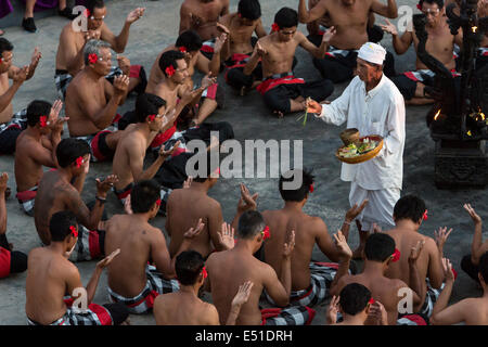 Bali, Indonesien.  Hindu Priester besprüht Wasser auf Tänzer in den Kecak-Tanz, Arena neben Uluwatu Tempel. Stockfoto