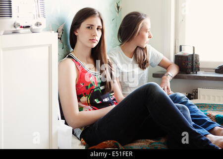 Junge Frau und Teenager (16-17) sitzen auf Bett Stockfoto