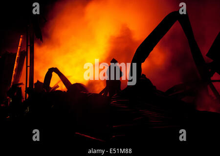 Silhouette der Feuerwehrleute kämpfen ein wütendes Feuer Stockfoto