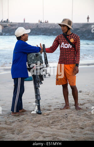 Jimbaran, Bali, Indonesien.  Zwei Fischer begrüßen einander am Strand, am frühen Morgen. Stockfoto