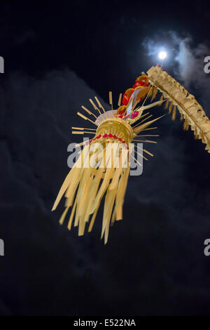 Bali, Indonesien.  Volle Mond und ein Penjor (gebogene Bambusstange mit Palm Frond Dekorationen), religiösen Anlass. Stockfoto