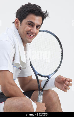 Porträt von glücklich Tennisspieler hält Schläger auf grauem Hintergrund isoliert Stockfoto
