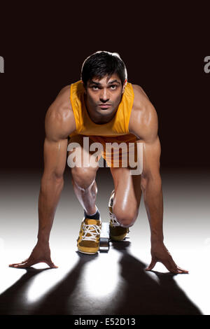 Junge männliche Läufer bereit, sprint aus Startlöchern auf schwarzem Hintergrund Stockfoto