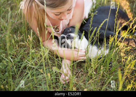 Ein Mädchen umarmt einen schwarzen und weißen Hund im Park. Stockfoto
