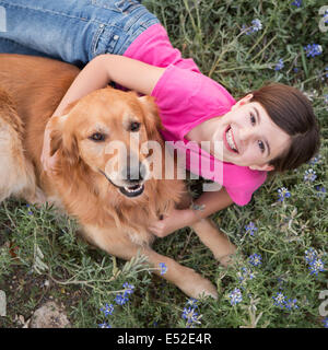 Ein junges Mädchen umarmt ein golden Retriever-Haustier. Stockfoto