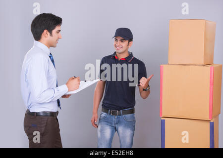 Lieferbote liefern Paket Geschäftsmann vor grauem Hintergrund Stockfoto