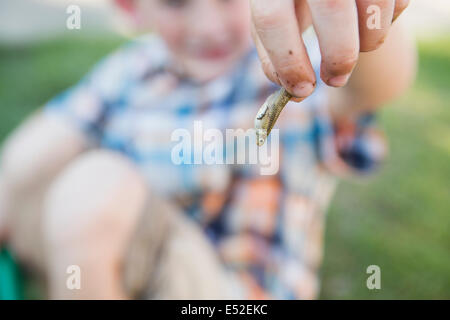 Ein kleiner Junge, ein kleiner Fisch in den Fingern hält. Stockfoto