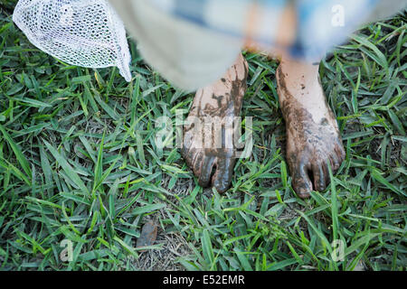 Ein Junge mit schlammigen Füßen stehend an einem Flussufer. Stockfoto